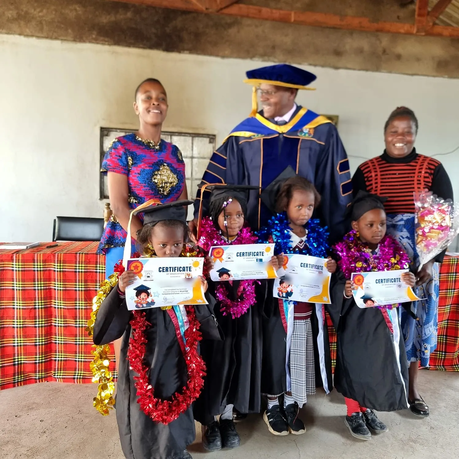 Pre-school graduates in gowns with their teachers on graduation day
